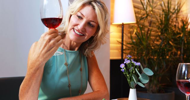 Smiling woman enjoying red wine at table in modern restaurant - Download Free Stock Images Pikwizard.com