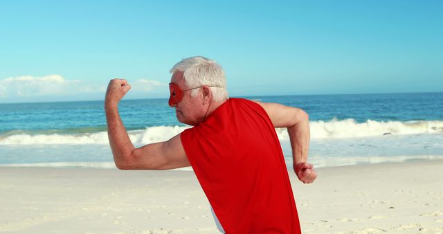 Elderly Man in Superhero Costume Flexing on Sunny Beach - Download Free Stock Images Pikwizard.com