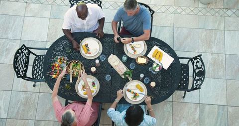 Diverse Friends Enjoying Outdoor Dinner with Grilled Skewers