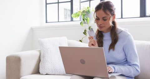 Mid adult woman online shopping with credit card on laptop