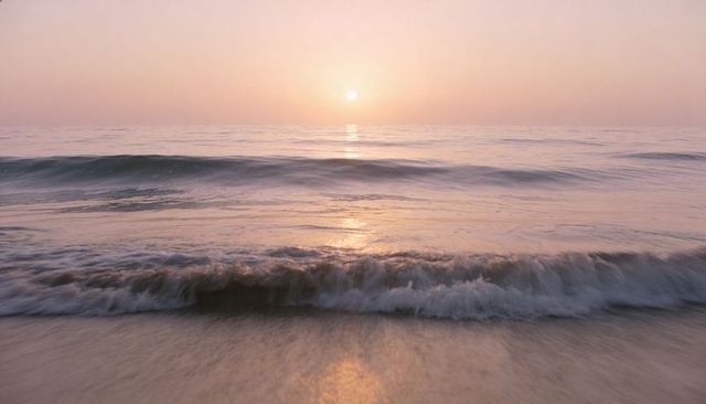 Rolling waves reflecting sunrise over pastel sandy shoreline