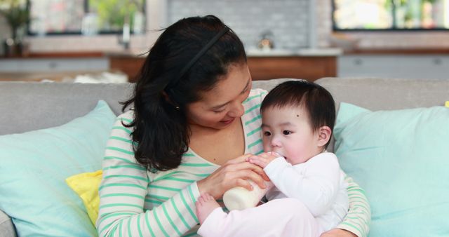 Mother Feeding Baby with Bottle on Sofa at Home - Download Free Stock Images Pikwizard.com