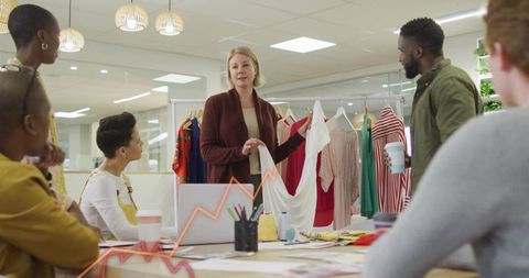 Fashion team presenting garment during collaborative design meeting with fabric swatches