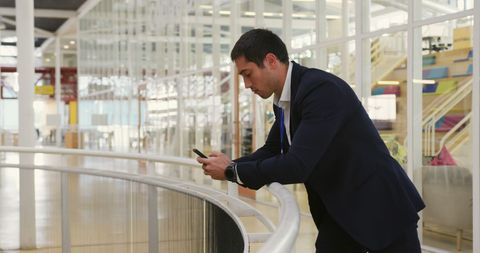 Businessman Focused on Phone in Spacious Modern Office Environment