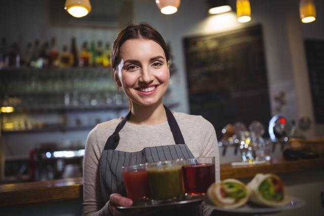 Portrait of waitress holding plate of juices in cafÃ©