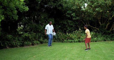 Father and son playing soccer in backyard practicing passing and ball control family fitness