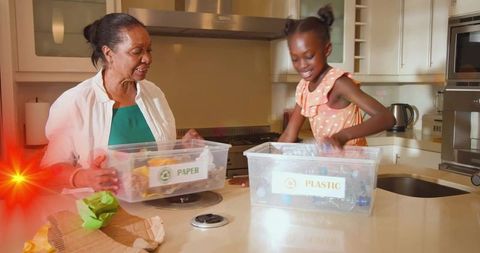 Grandmother and granddaughter sorting recycling bins in kitchen teaching family eco habits