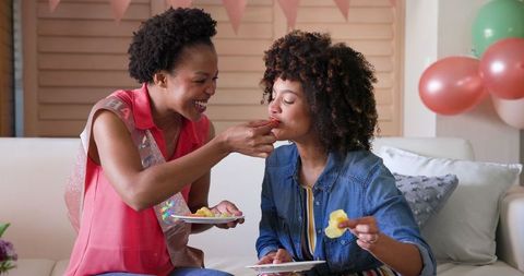 Joyful Female Couple Enjoying Snacks During Celebration