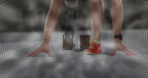 Male sprinter crouching at starting blocks with carbon running blade for explosive start