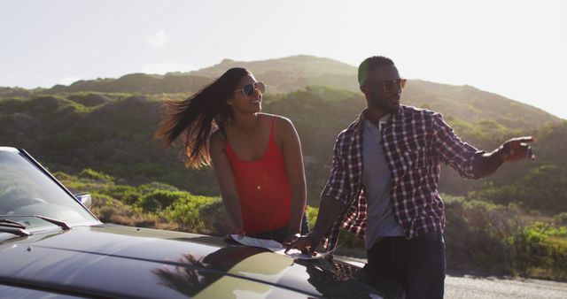 Perfect for travel and adventure themes, this image shows a couple enjoying a scenic road trip in a convertible under sunlight. They appear relaxed and happy, making it ideal for vacation advertisements, travel blogs, or adventure promotions.