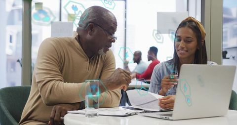 Senior African American Mentor Collaborating with Indian Colleague Over Laptop and Documents