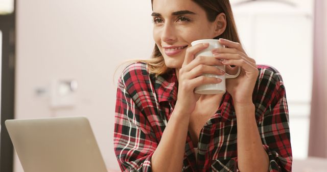 Woman Enjoying Coffee While Working on Laptop in Cozy Home - Download Free Stock Images Pikwizard.com