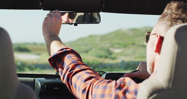 Man Driving Convertible Car Adjusting Rearview Mirror During Road Trip - Download Free Stock Images Pikwizard.com