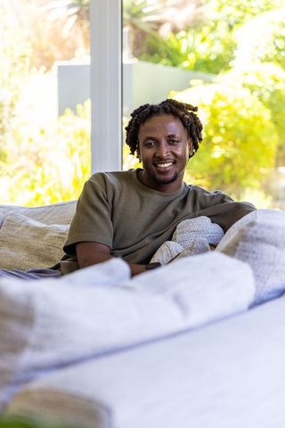 African american man relaxing on sunlit sofa by window, casual home lifestyle portrait
