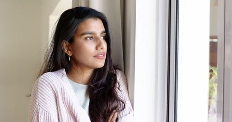 Thoughtful Woman Gazing Out Window Surrounded by Peaceful Minimalist Interior