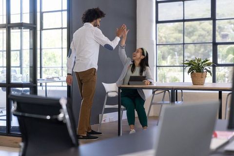 Diverse Colleagues High-Fiving at Modern Office Desk