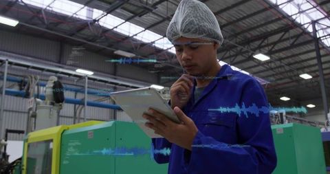 Factory technician inspecting tablet with analytics overlays monitoring line efficiency