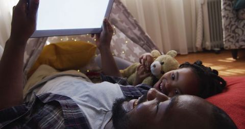 Father and Daughter Enjoying Tablet Time in Cozy Blanket Fort
