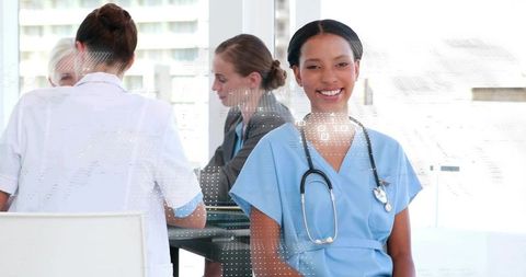 Smiling nurse leading clinical team meeting in modern hospital conference room