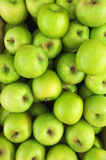 Fresh green apples packed in a box. Suitable for use in advertisements related to healthy eating, vegan diets, farmers markets, and organic food promotions. Can also be used for recipes, cooking blogs, nutrition content, or as a vibrant kitchen decoration.