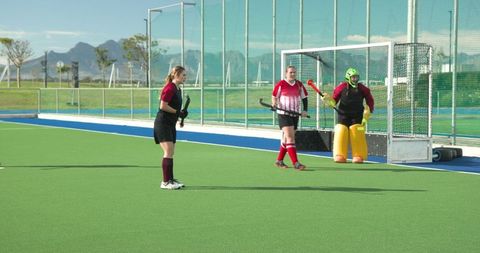 Female field hockey team members strategizing on turf field