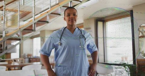 Confident female nurse standing in modern loft wearing scrubs and stethoscope in daylight