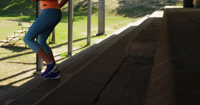 A woman in bright athletic wear running up concrete steps outdoors during sunset. Use this for fitness, lifestyle, health, exercise promotions, or illustrating athletic topics in blogs and social media.