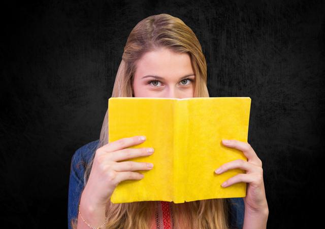 Portrait of woman holding a book against black background