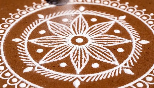 Creating white rangoli mandala on brown surface closeup kolam powder art