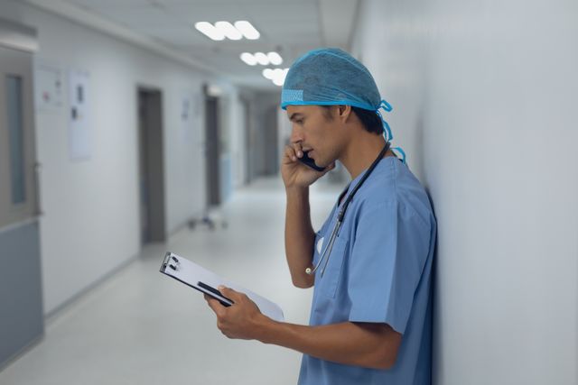 Male surgeon talking on mobile phone in the corridor at hospital