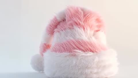 Zooming closeup revealing fluffy pink-white fur beanie with pompom and light sparkles