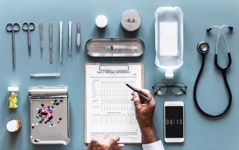 Medical tools and daily report schedule on gray desk