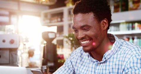 Smiling Man Using Smartphone at Cozy Cafe