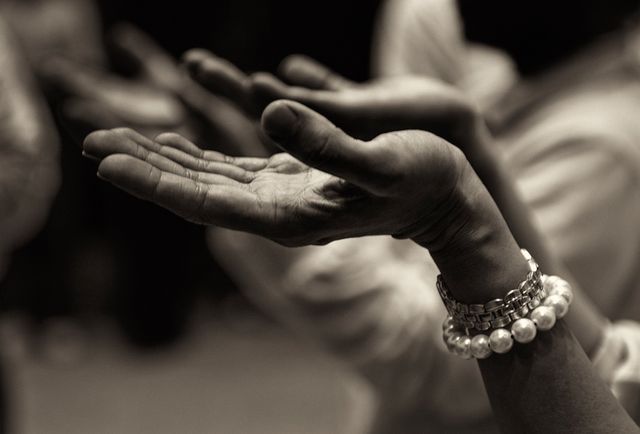 Monochrome close-up of hands held open in a prayer or meditation gesture. The image captures the essence of spirituality and tranquility. It highlights the fine details of the fingers and veins, along with a pearl bracelet adding a touch of elegance. Ideal for use in articles or presentations about mindfulness, spiritual practices, faith, or meditative techniques.