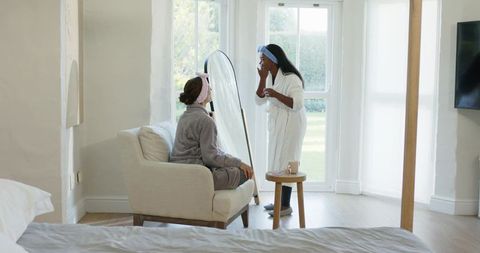 Diverse friends enjoying skincare ritual in cozy bedroom