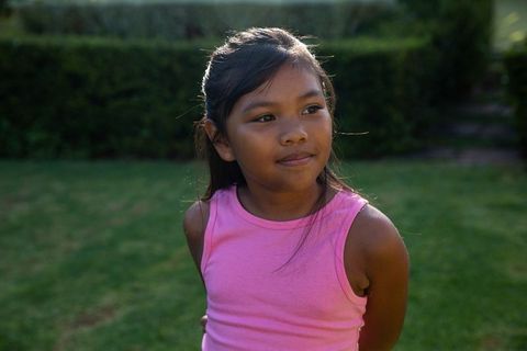 Thoughtful Girl in Pink Top Standing in Lush Backyard