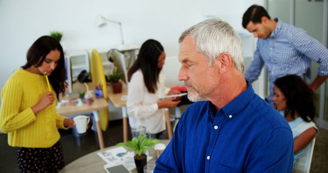 Mature Businessman Reflecting While Team Works in Casual Office - Download Free Stock Images Pikwizard.com