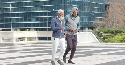 African american senior men walking briskly together in urban plaza for healthy living