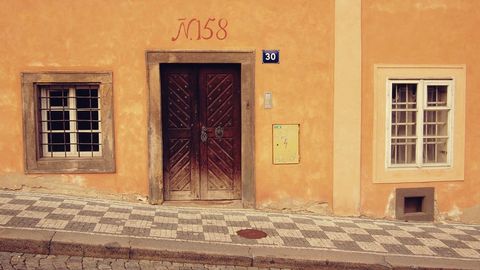 Featuring rustic orange facade featuring ornate wooden door and patterned cobblestone sidewalk