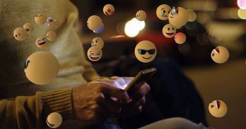 Emoticons hovering over smartphone of senior user