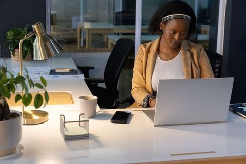 African american woman working on laptop at modern minimalist office desk, professional