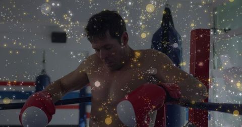 Exhausted boxer resting on ring ropes with red gloves showing focus and determination
