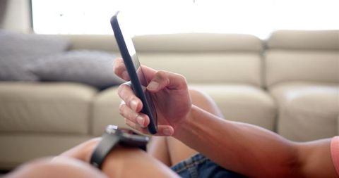 Young Adult Engaging with Smartphone Relaxing on Couch
