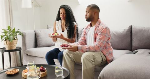Happy Couple Relaxing with Snacks in Sunlit Living Room