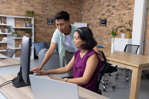 Collaborative office environment with coworkers discussing at desk