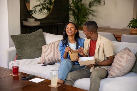Happy Couple Sharing Takeout on Cozy Living Room Couch