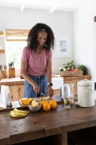 African american woman chopping fruit on rustic kitchen island for healthy smoothie