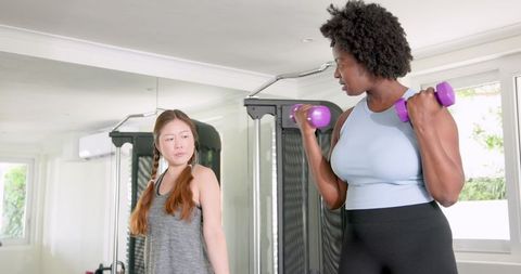 Diverse Women Engaging in Dumbbell Workout at Gym