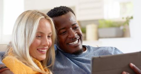 Smiling Couple Enjoys Time Together with Digital Tablet in Cozy Living Room