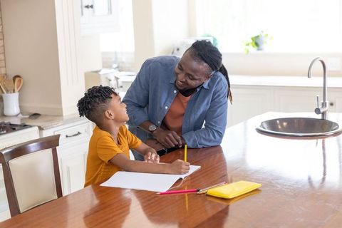 Father helping son with homework at kitchen island smiling mentorship in daylight